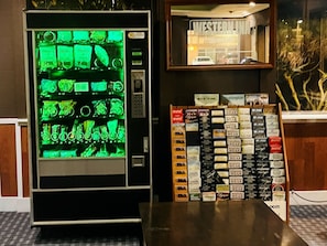 A vending machine with green-lit items and a display of books titled 'Western Wear' and 'Family Adventures.'
