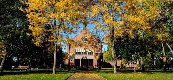 A building with a central tower and arched windows, surrounded by trees with yellow leaves.