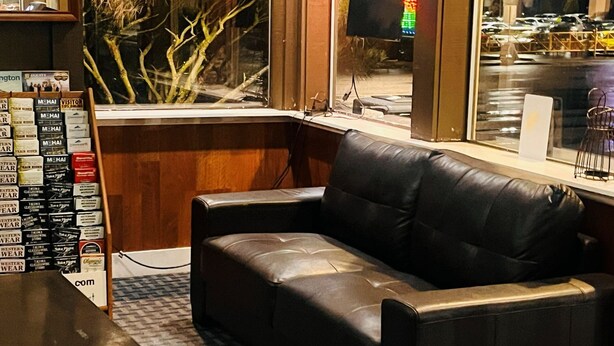 A corner seating area with a leather sofa, a small table, and a display of Western Wear clothing.