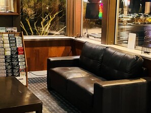 A corner seating area with a leather sofa, a small table, and a display of Western Wear clothing.