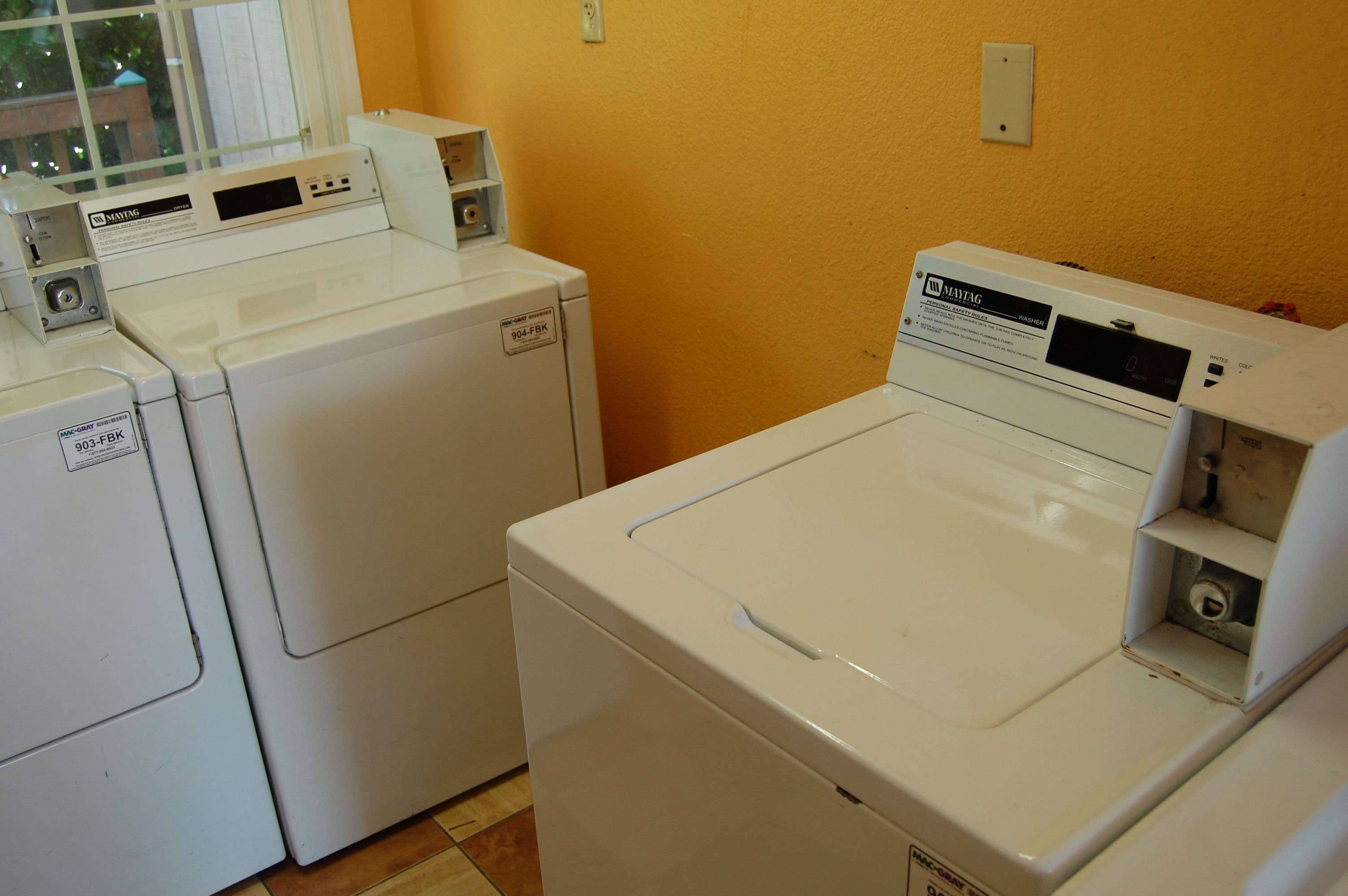 A laundry room with three white front-loading washers and dryers.