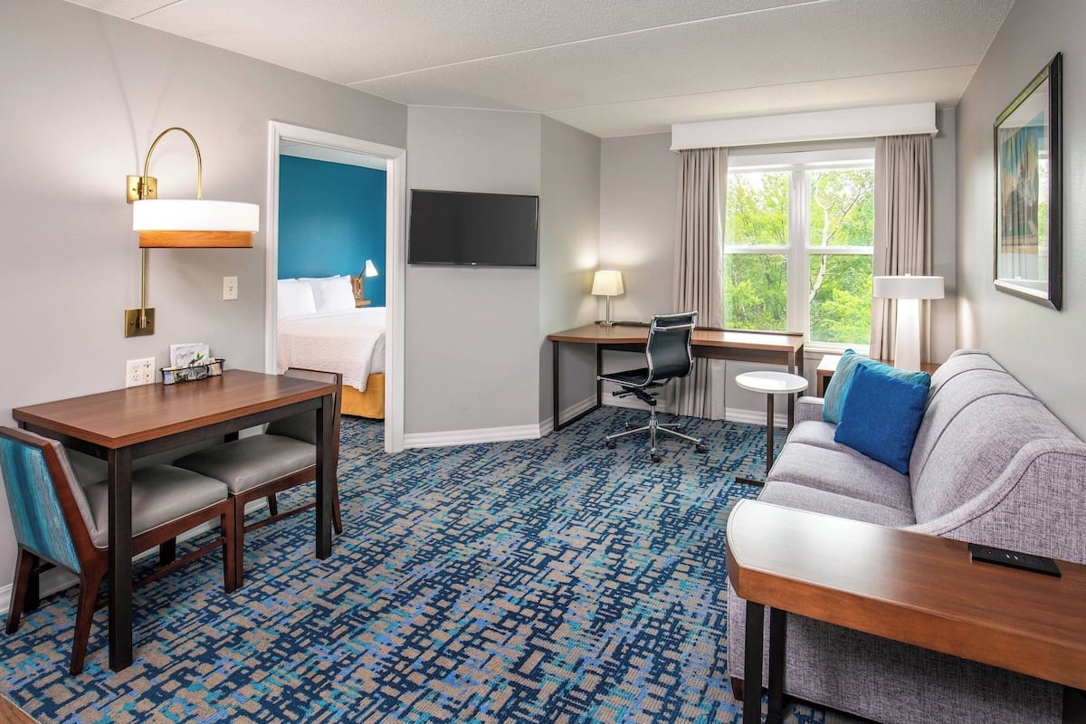 A hotel room with a bed, a desk, a sofa, a TV, and a window with curtains.