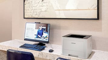 A desk with a computer monitor, keyboard, and printer.