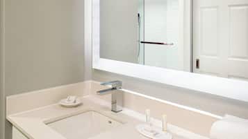 A bathroom with a beige countertop, a sink, a mirror, and a towel rack.
