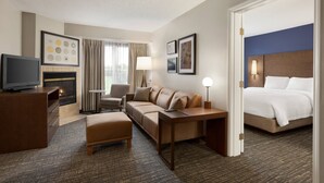 Ein Hotelzimmer mit Sofa, Schreibtisch, Fernseher, Bett und Kamin.