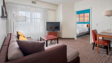 Habitación de hotel con sofá, televisor, una mesita, cama y silla.