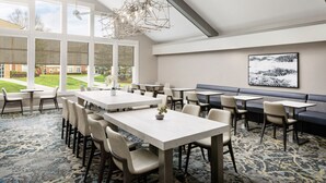 A spacious dining area with high ceilings, large windows, and a modern chandelier. Tables and chairs are arranged for dining. - Residence Inn by Marriott Saddle River (Saddle River)