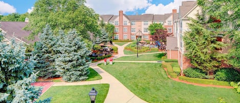 A residential area with a well-maintained lawn, a pathway, and a brick building with multiple windows.