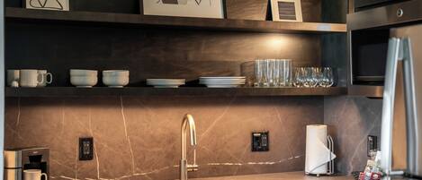 A modern kitchen with a built-in espresso machine, a stainless steel sink, and a marble backsplash.
