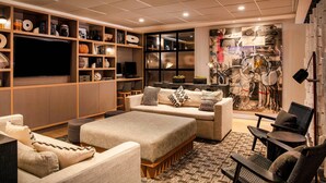 Un salon moderne doté d’un grand téléviseur à écran plat, de sièges confortables et d’une bibliothèque remplie d’objets décoratifs.