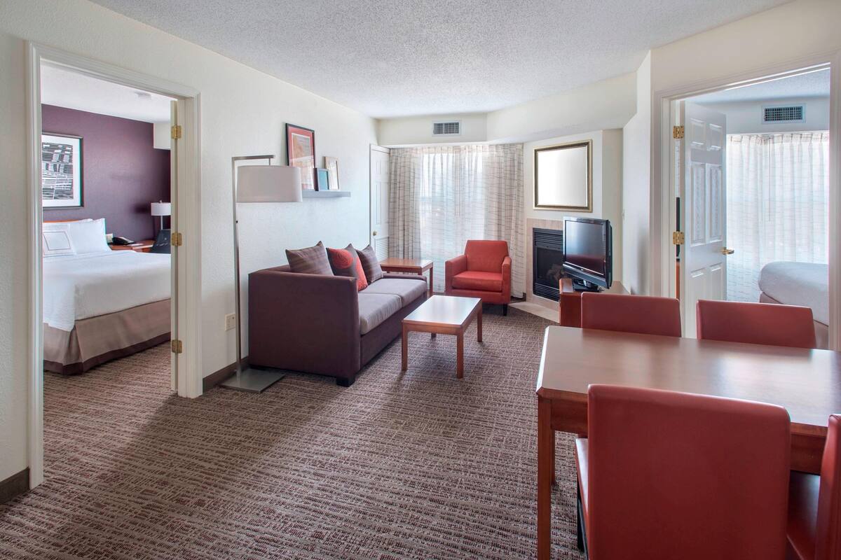 Ein Hotelzimmer mit Bett, Sofa, Fernseher, Kamin und Essecke.