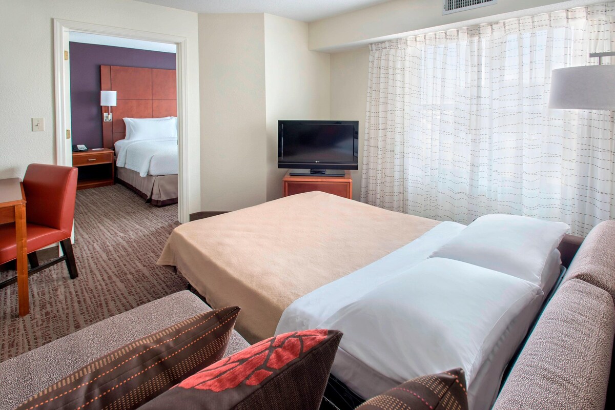 A hotel room with a bed, a television, a desk, and a chair.