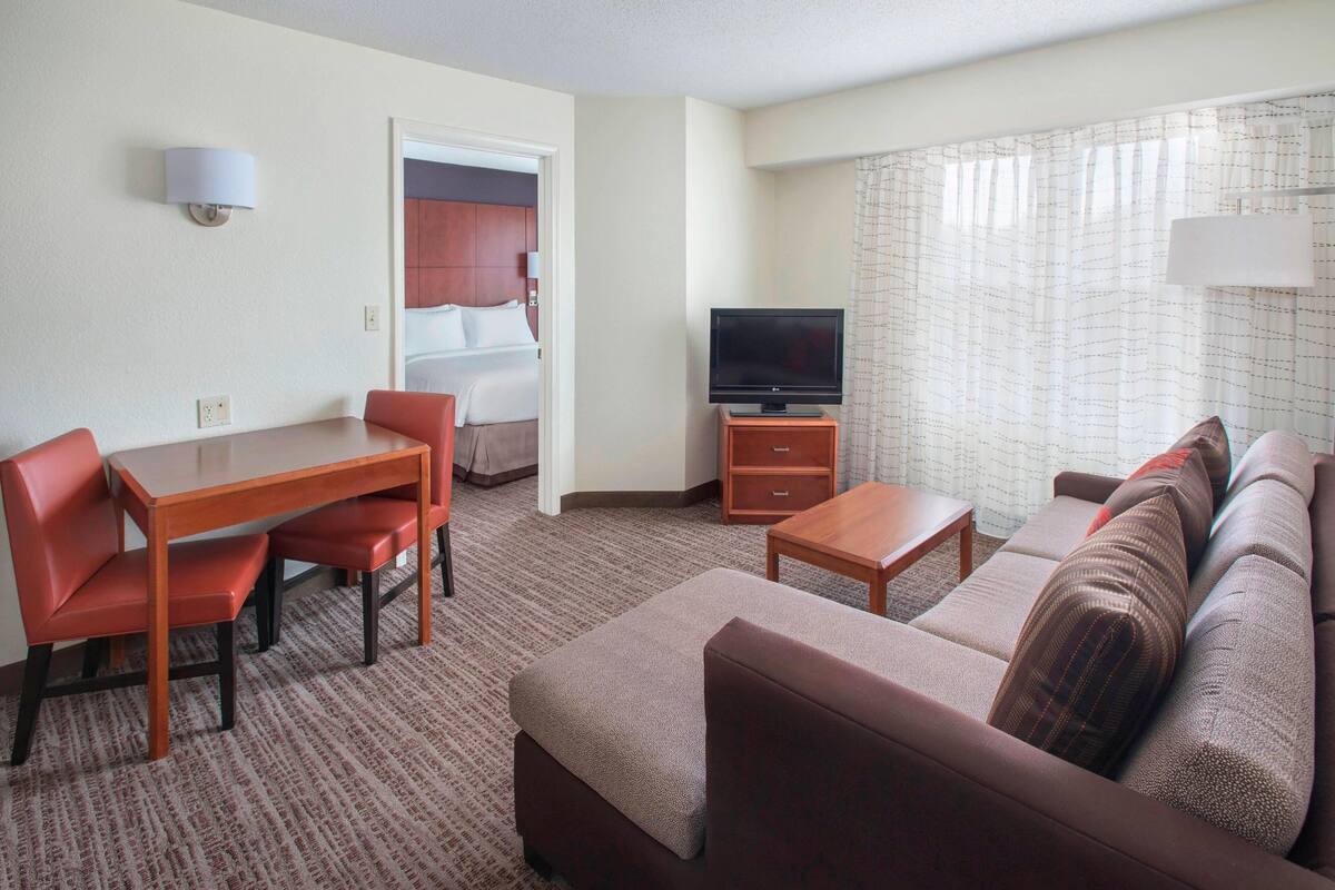 Ein Hotelzimmer mit Essbereich, einer Sitzecke, einem Fernseher und einem Bett.