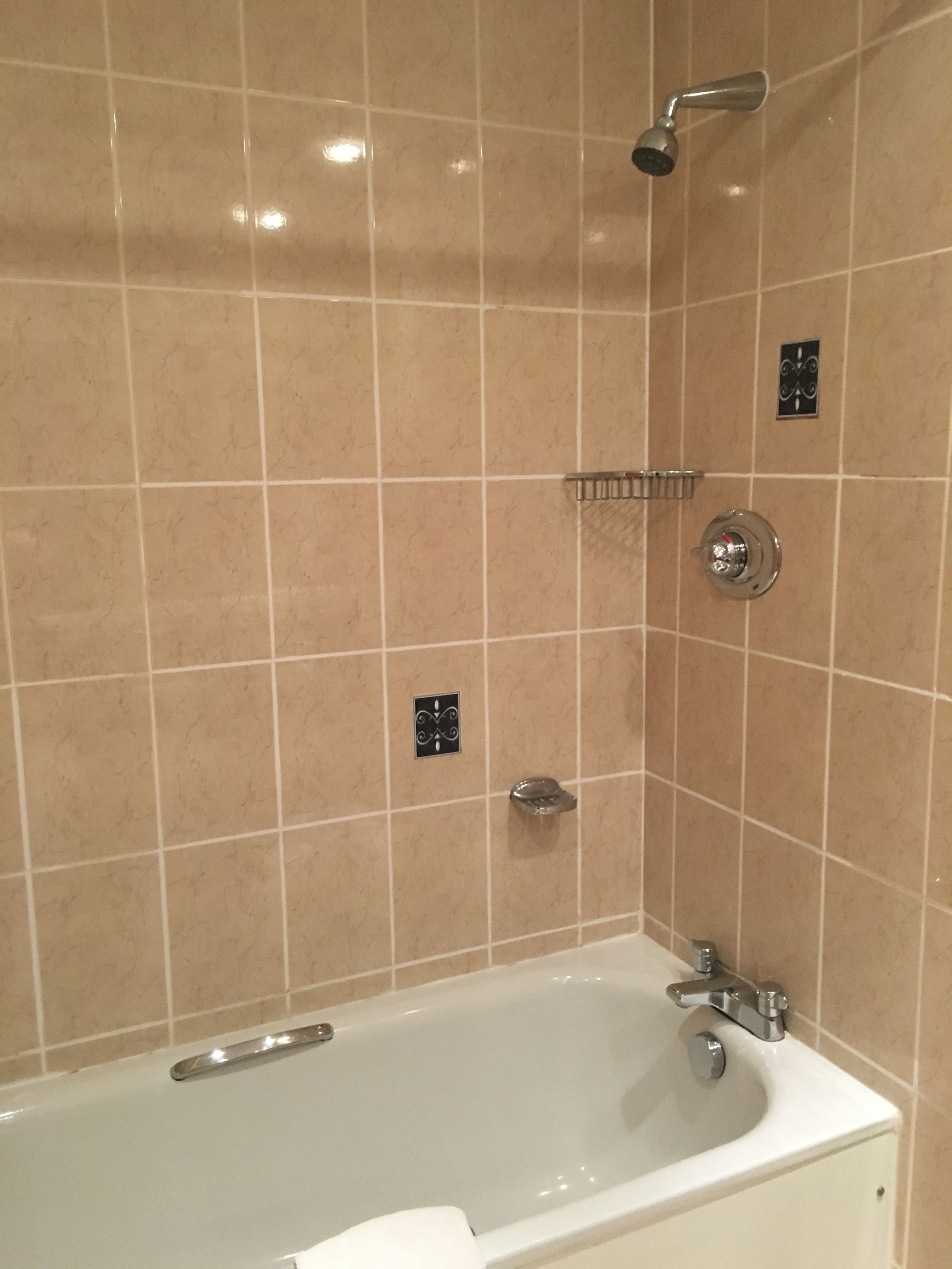 A bathroom with a bathtub, shower, and tiled walls.