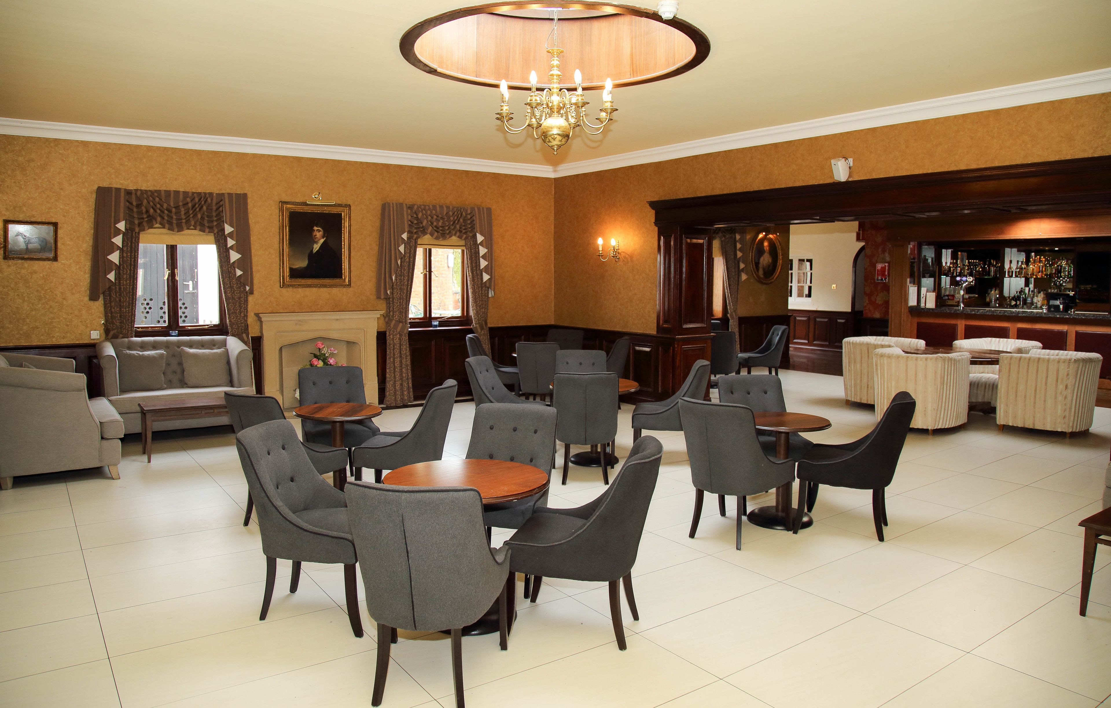 Een hotel lobby met verschillende zithoeken, een bar en een open haard.