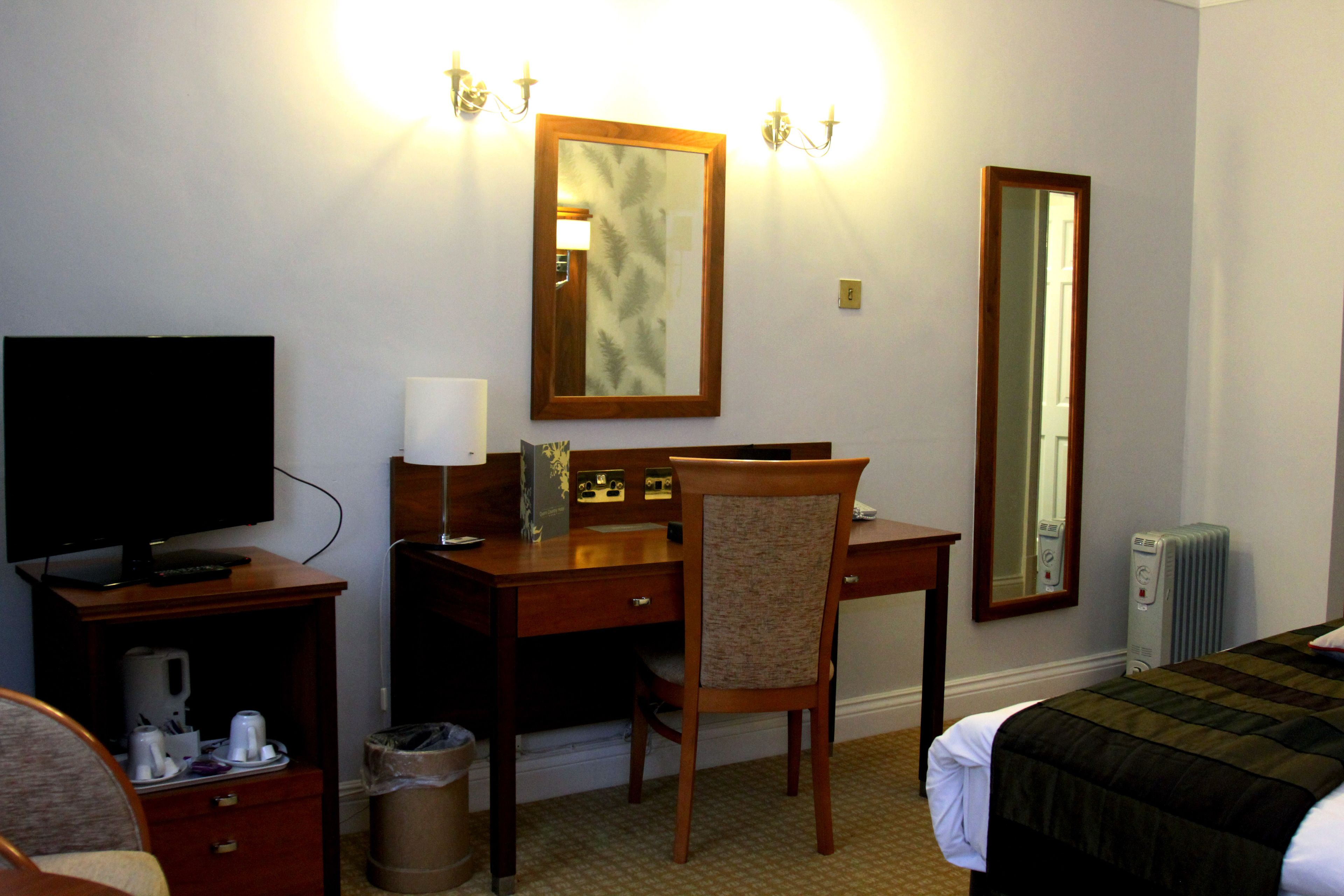 Una habitación de hotel con escritorio, silla, televisión y cama.