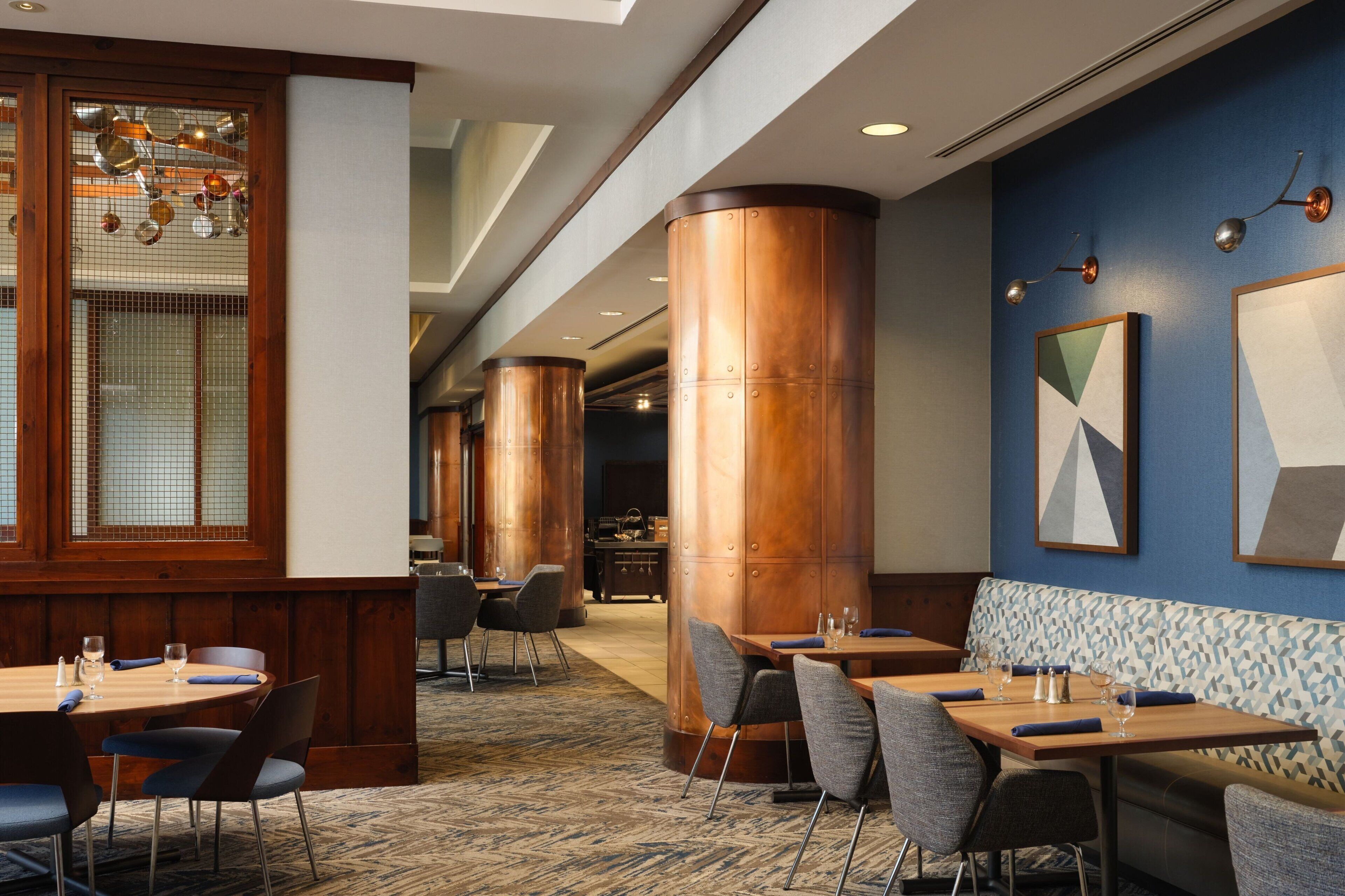 A hotel lobby with wooden paneling, large copper columns, and modern furniture.
