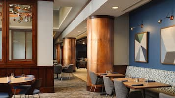 A hotel lobby with wooden paneling, large copper columns, and modern furniture.
