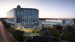 A modern hotel with a prominent glass facade, a central tower, and a spacious parking area. - Sheraton Myrtle Beach (Myrtle Beach)