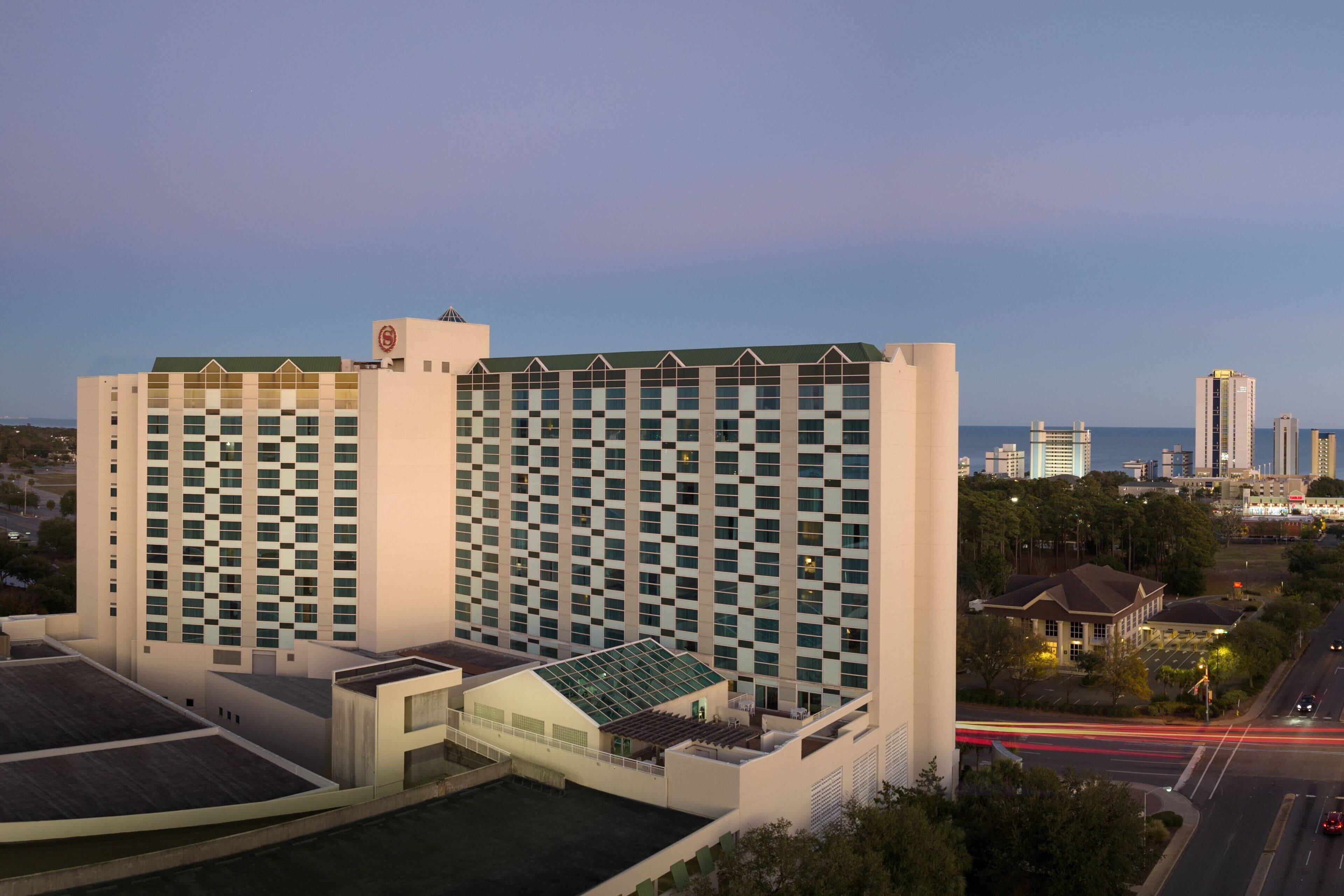 Un hotel moderno de gran altura con fachada a cuadros, varios pisos y una terraza en la azotea.