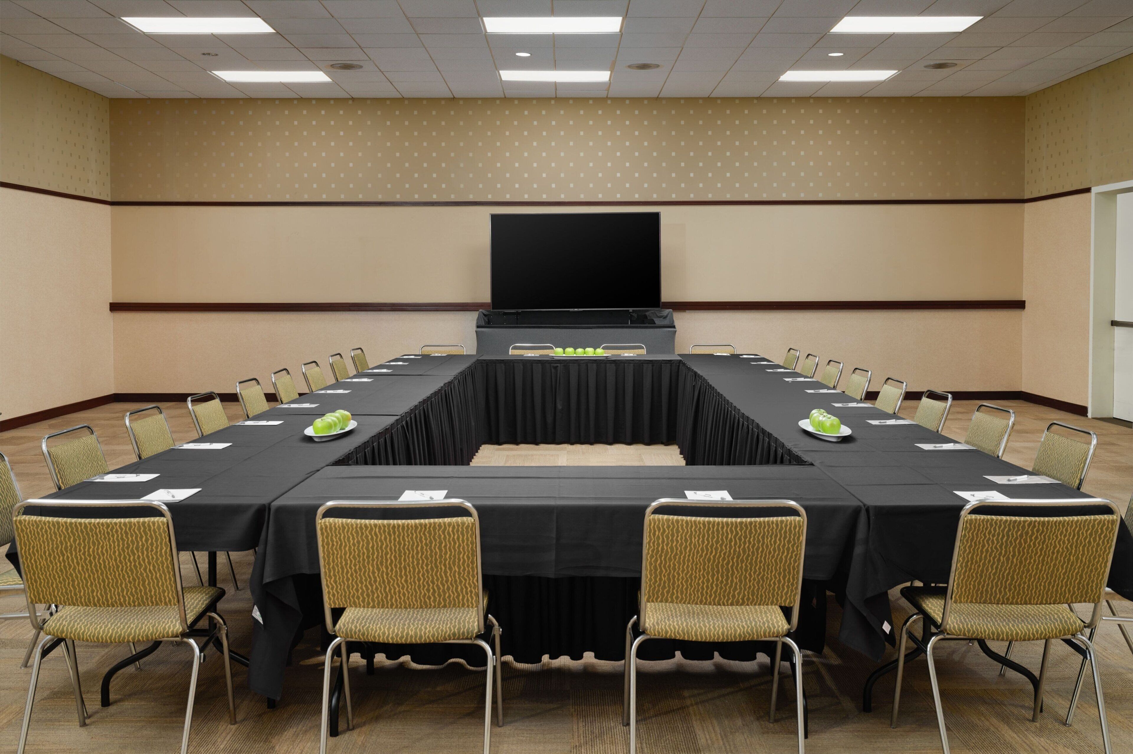 A conference room with a long table, chairs, a screen, and a projector.
