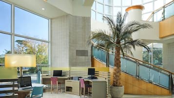 A spacious lobby with a high ceiling, large windows, and a central staircase.