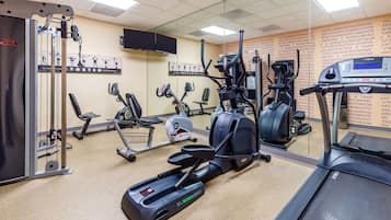 Ein Fitnessstudio mit verschiedenen Trainingsgeräten, darunter Laufbänder, Crosstrainer und Kraftgeräte.
