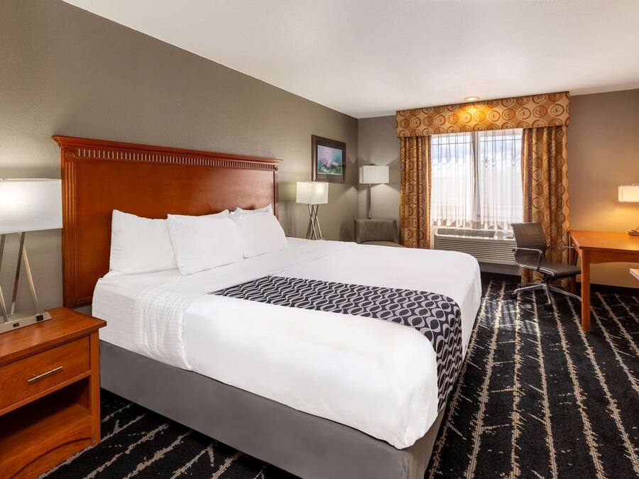A hotel room with a large bed, a desk, a chair, and a television.