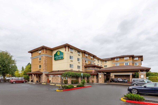 Ein La Quinta Inn & Suites Hotel mit Parkplatz und überdachter Eingangszone.