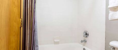 A bathroom with a bathtub, a toilet, and a shower curtain.