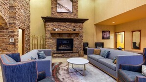 A spacious living area with a stone fireplace, two sofas, and a coffee table. - La Quinta Inn & Suites by Wyndham Vancouver (Vancouver)