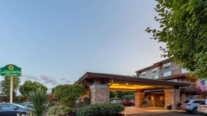 A La Quinta Inn & Suites with a stone facade, a covered entrance, and a parking lot with cars. - La Quinta Inn & Suites by Wyndham Vancouver (Vancouver)