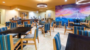 A restaurant with multiple tables and booths, a counter with a coffee machine, and a mural on the wall. - La Quinta Inn & Suites by Wyndham Vancouver (Vancouver)