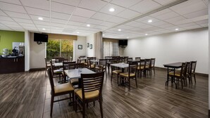 A conference room with multiple tables and chairs, a kitchen area with a coffee machine, and a large window with a view of greenery. - Sleep Inn & Suites Valdosta Mall Area (Valdosta)