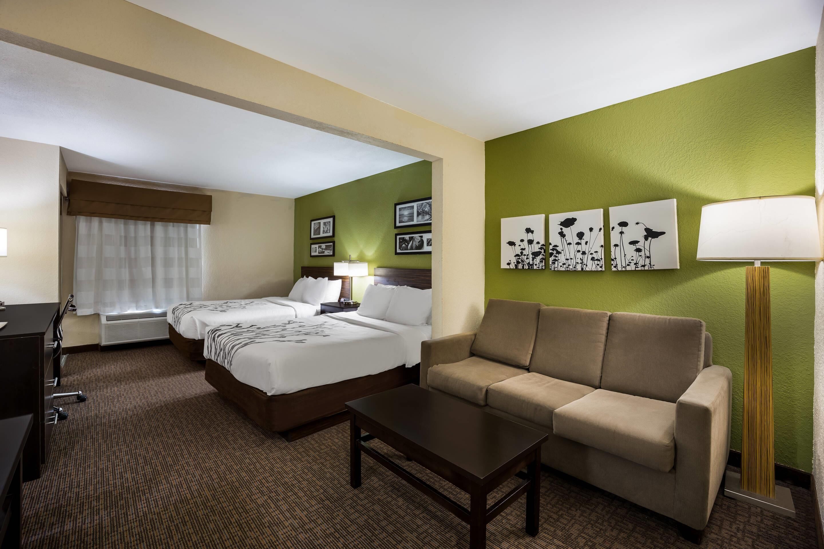 Ein Hotelzimmer mit Bett, zwei Nachttischen, einer Couch, einem Couchtisch und Wandbildern.