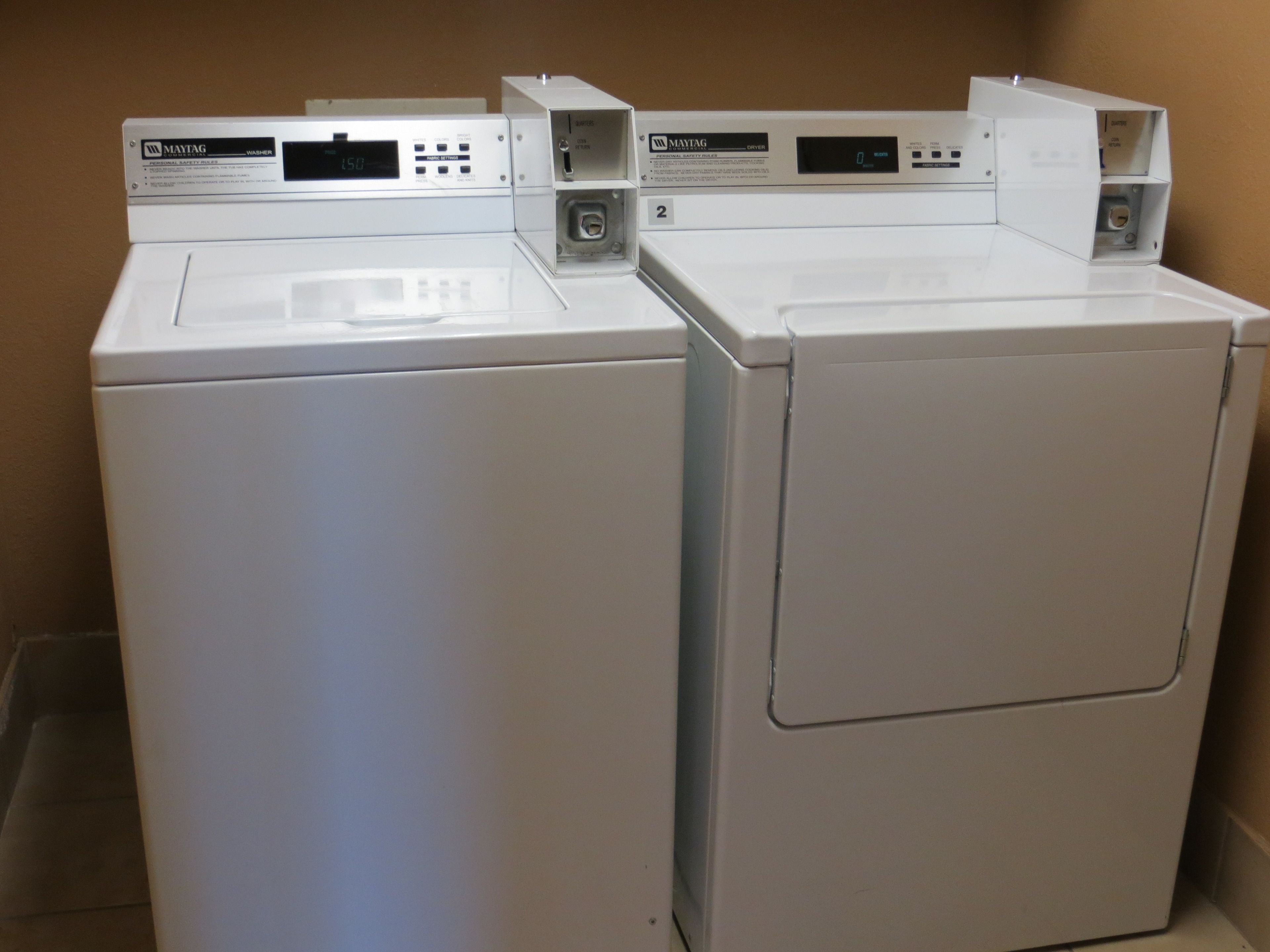 Two white Maytag front-loading washing machines in a laundry room.
