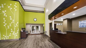 A reception area with a green wall, a clock, and a reception desk. - Sleep Inn & Suites Valdosta Mall Area (Valdosta)