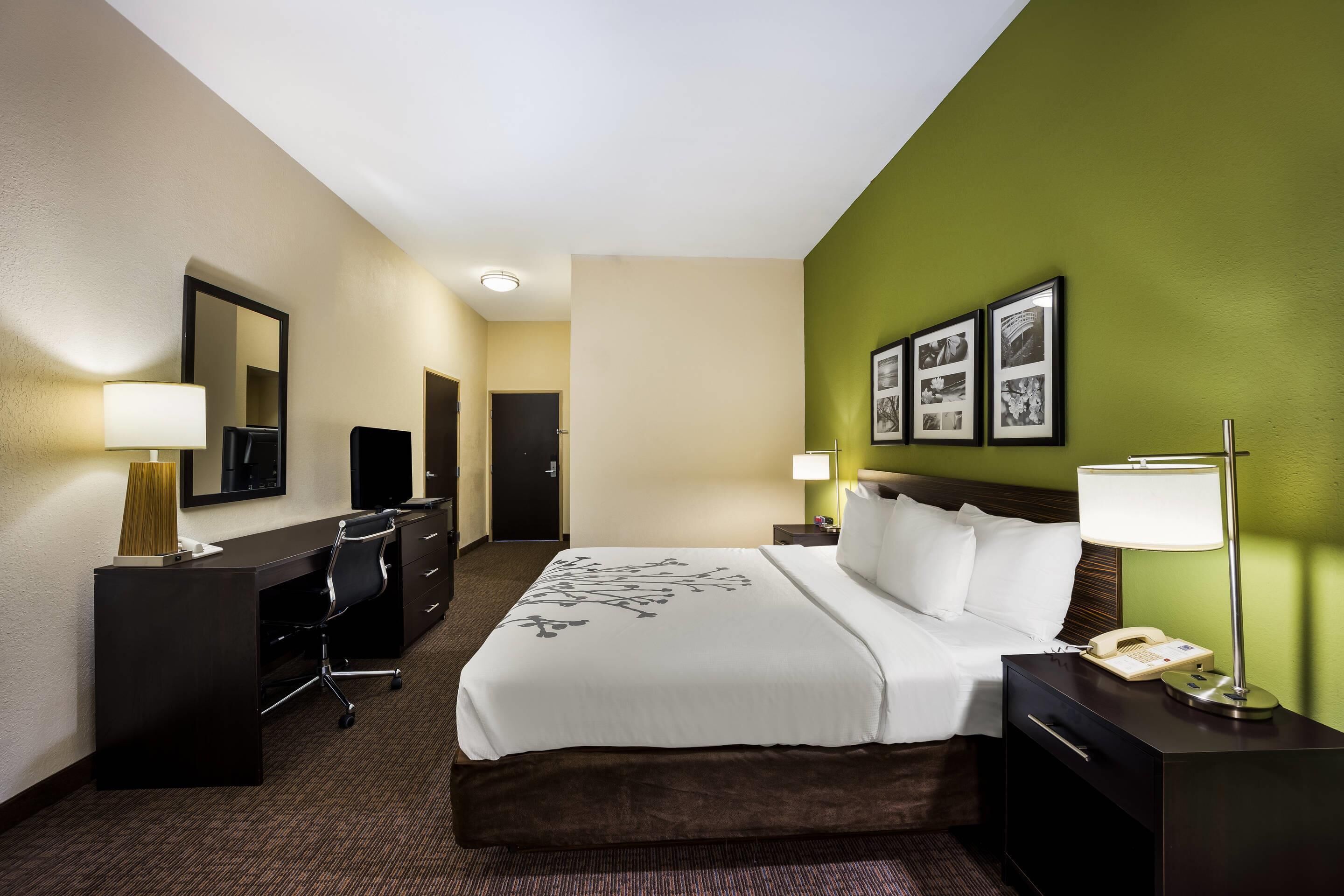 Habitación de hotel con cama, escritorio, silla y dos mesitas de noche con lámparas.