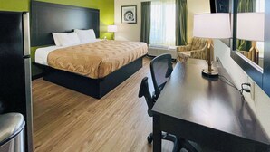 A hotel room with a large bed, a desk, a chair, a TV, and a window with curtains. - Quality Inn & Suites Lake Charles South (Lake Charles)