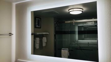 A bathroom with a large mirror, a towel rack, and a shower area.