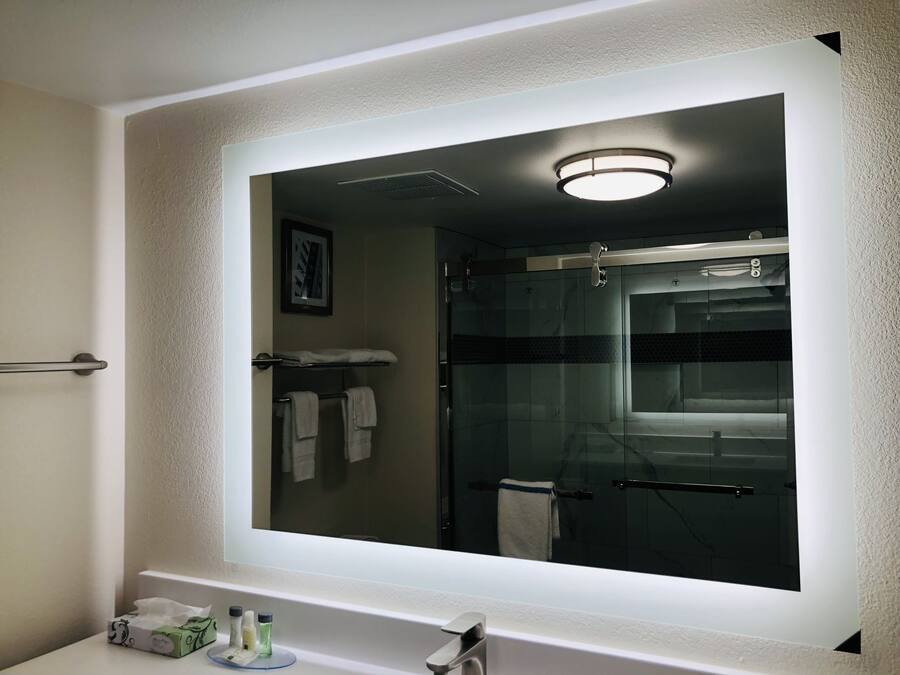A bathroom with a large mirror, a towel rack, and a shower area.