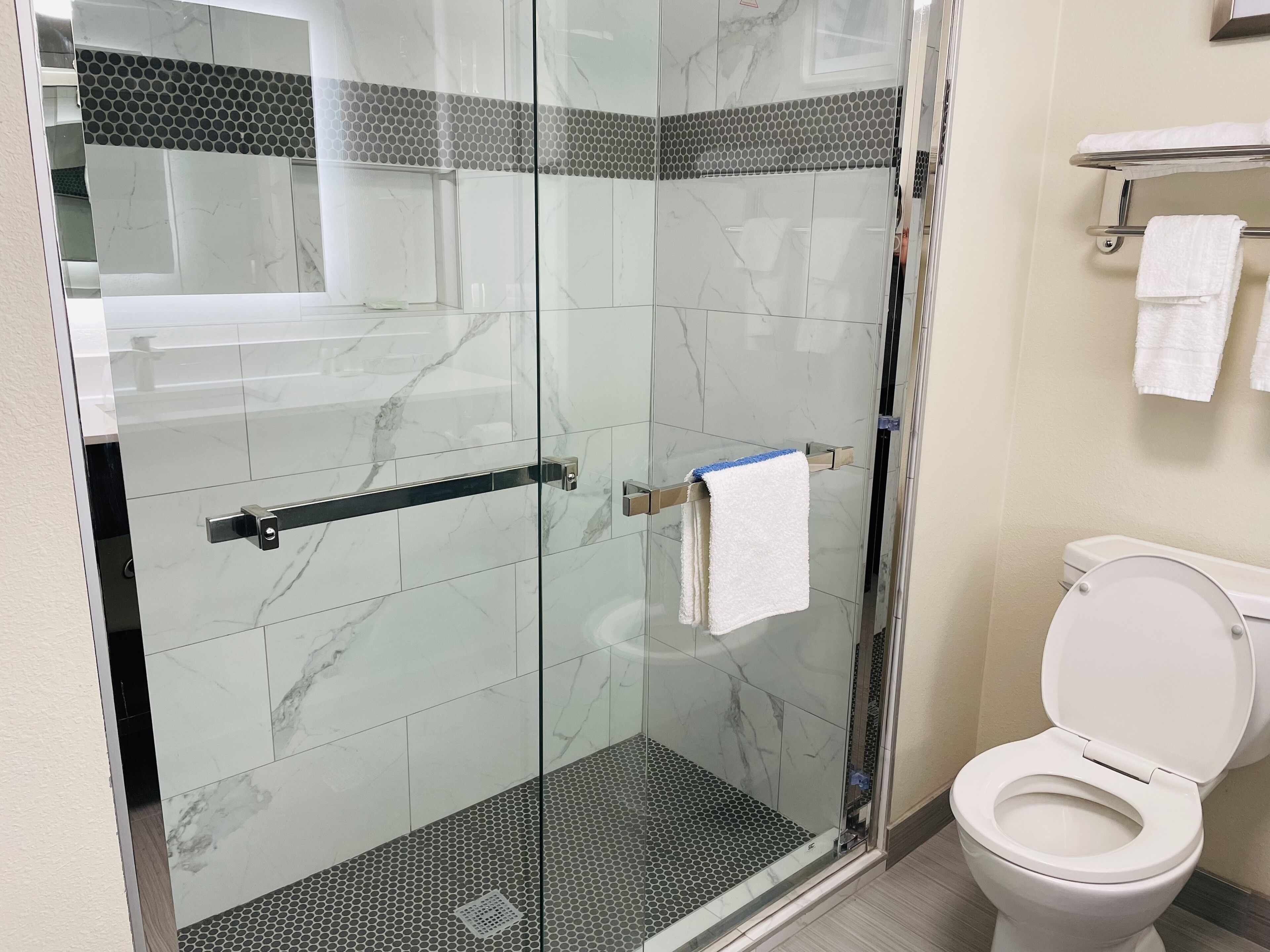 Ein modernes Badezimmer mit Duschkabine, Toilette und Handtuchhalter.
