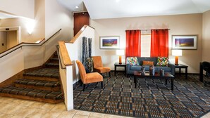 A hotel lobby with a staircase, a sofa set, a coffee table, and two framed pictures on the wall. - Quality Inn & Suites Lake Charles South (Lake Charles)