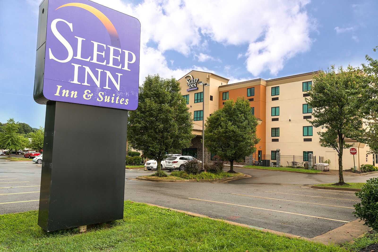 Une enseigne « Sleep Inn » devant un immeuble à plusieurs étages, avec un parking.