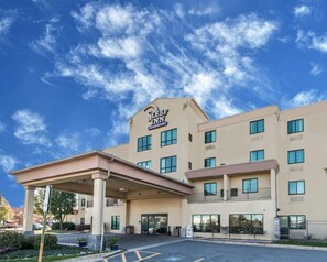 A Sleep Inn hotel with a covered entrance, multiple floors, and a clear blue sky with clouds.