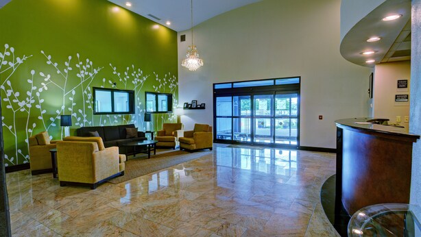 Eine Lobby mit grüner Wand, einer Rezeption und einer Sitzecke mit Sofas und Sesseln.