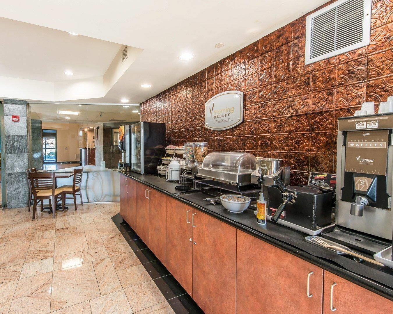 A breakfast bar with a coffee machine, a waffle maker, and a sign for 'Morning Medley'.