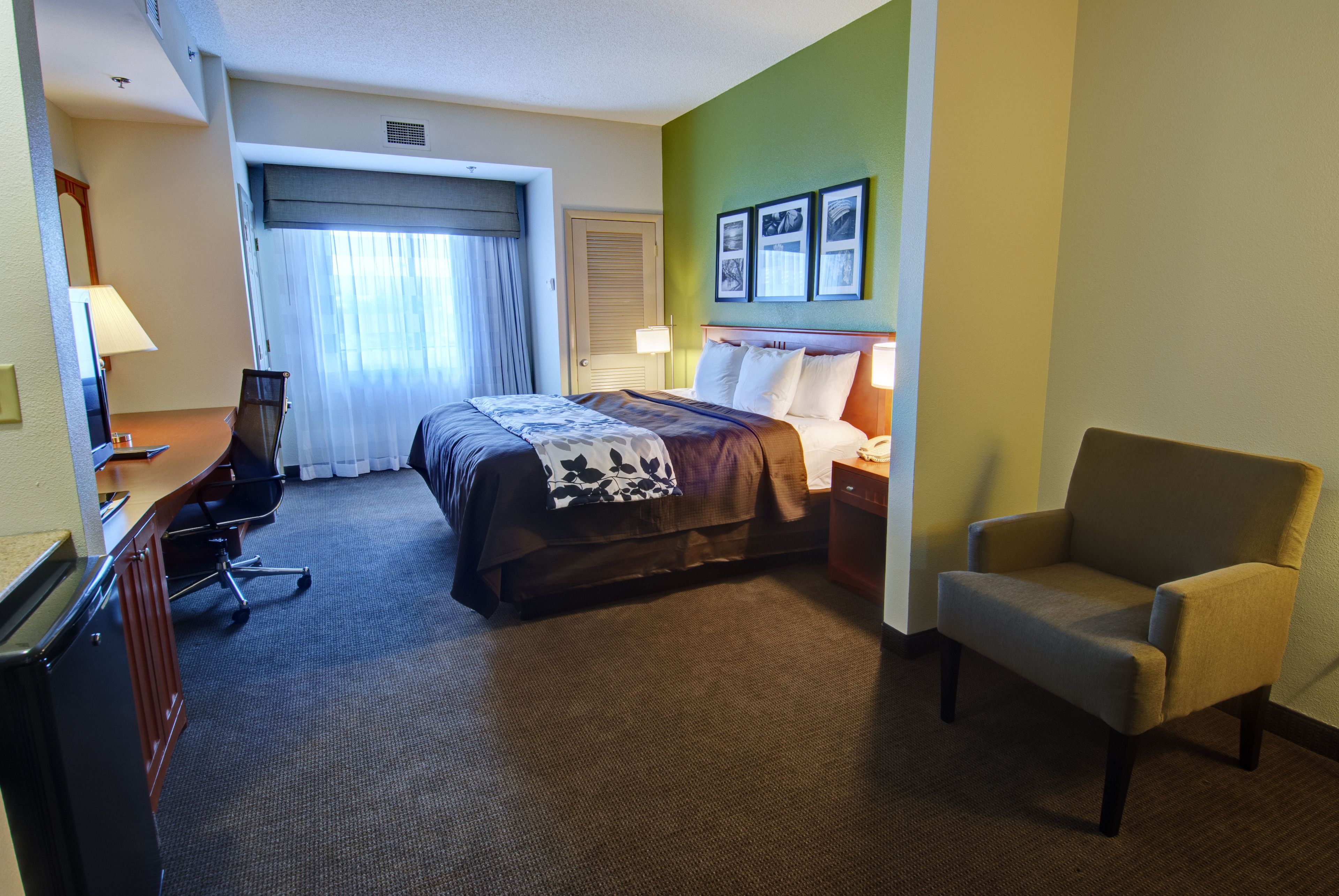 Una camera d'albergo con un letto, una scrivania, una sedia e un comodino.