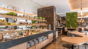 A buffet area with various food items, a coffee station, and seating arrangements. - Bavaria Boutique Hotel (Munich)