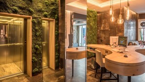 A modern hotel lobby with a green moss wall, a reception desk, and an elevator. - Bavaria Boutique Hotel (Munich)
